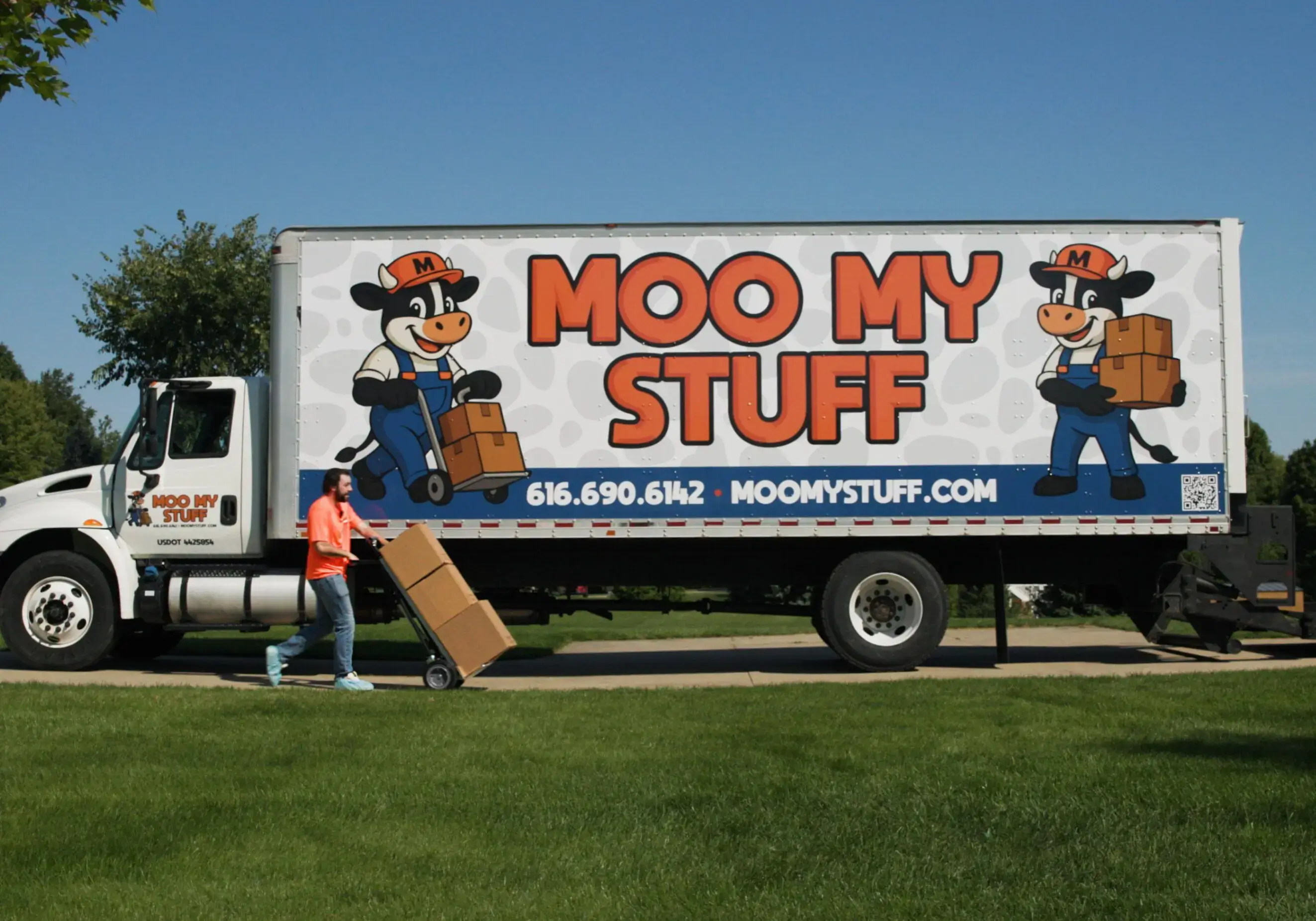 Moving truck with cartoon farmer and bold "Moo My Stuff" logo.